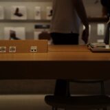 Mai multe laptopuri expuse pe o masă într-un magazin de electronice, cu ecranele aprinse