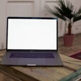Laptop cu un editor de cod deschis și un terminal, pe biroul unui student la informatică