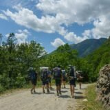 Chitară acustică sprijinită de un pat dintr-o cameră de cămin studențesc, lângă un caiet cu acorduri