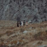 Grup de tineri cu rucsacuri care urcă pe o potecă marcată de munte, într-o zi senină de toamnă