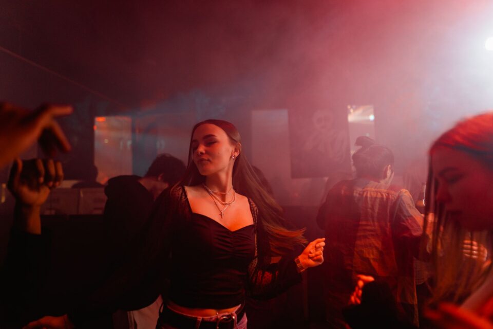 Studenți care dansează pe ringul unei săli decorate pentru balul bobocilor, sub lumini colorate